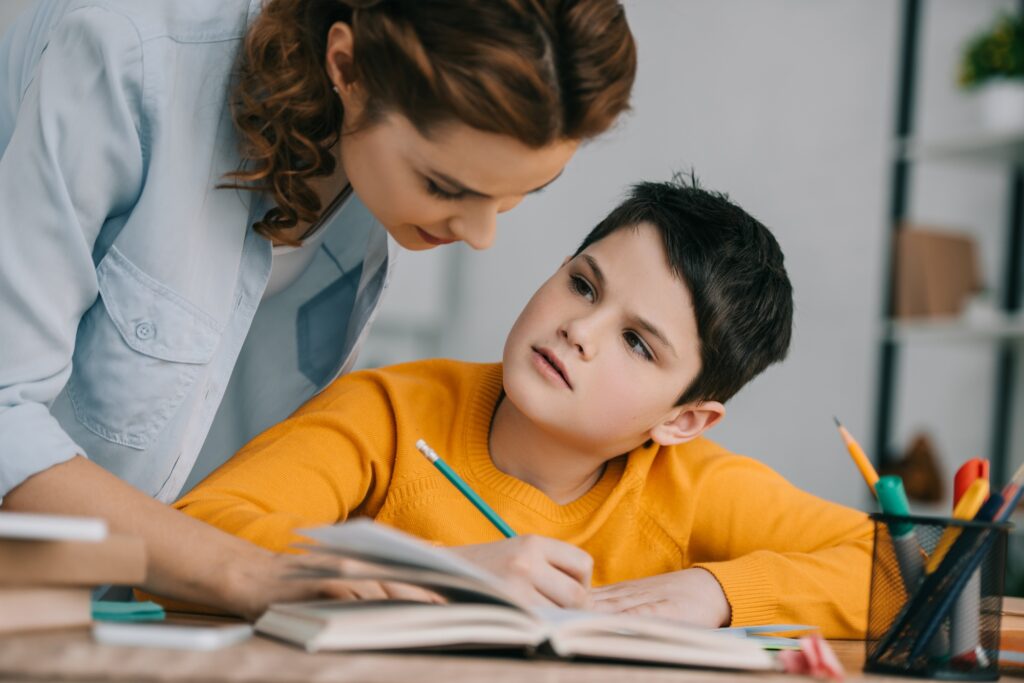 beautiful woman helping adorable son doing schoolwork at home
